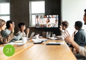Hybride Fuehrung - Konferenzraum - Leute sind präsent vor Ort und gleichzeitig sind Teilnehmer über Videokonferenz zugeschalten.